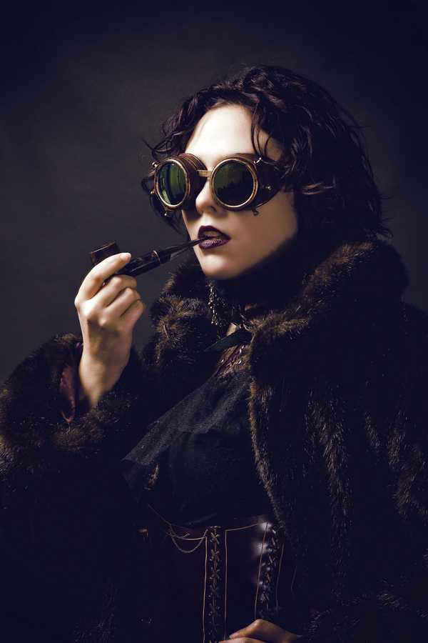Mujer con un atuendo de estilo steampunk que lleva gafas de aviador y una pipa de tabaco