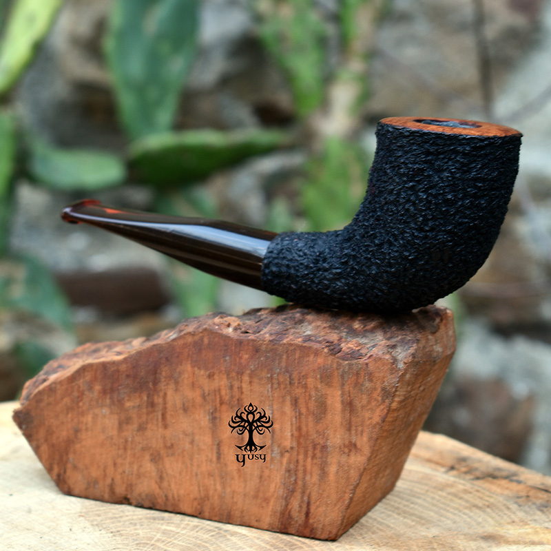 Pipa para tabaco Horn de Yusy Pipe Art con acabado rústico en negro azabache, corona lisa en color natural y boquilla acrílica ámbar.